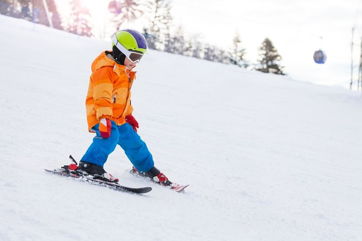 Bambino sulla pista da sci con il casco